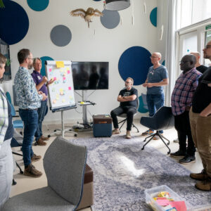 Een groepje medewerkers van TrailBlazers rondom een flipover tijdens een TrailBlazers-kwartaalmeeting op 20/8/2024.